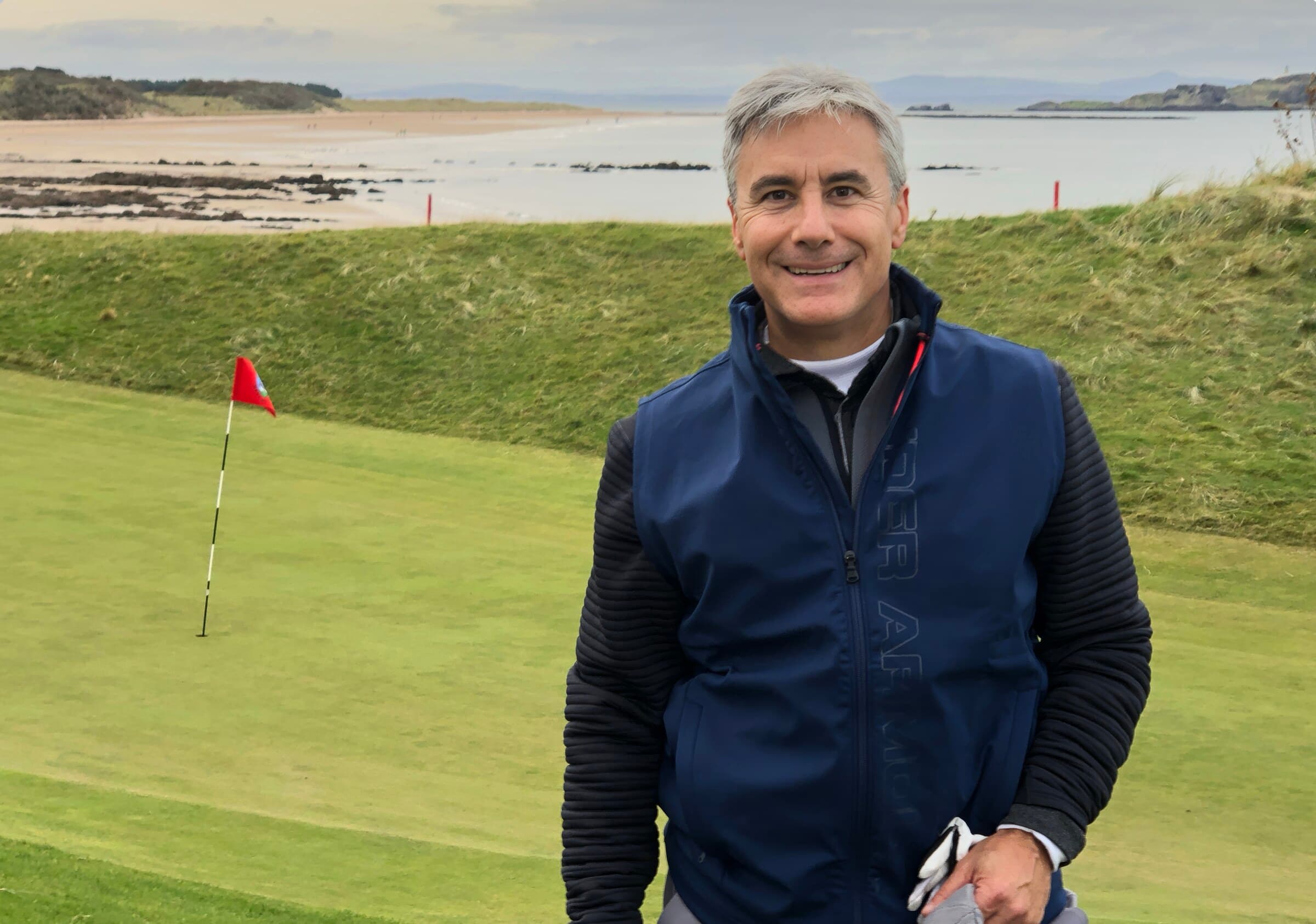 Scott Krim smiling on a golf course by the water